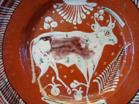 Mexican vintage pottery and ceramics, a bandera-ware charger with a wonderful bull, Tonala or Tlaquepaque, Jalisco, c. 1930's. The charger is decorated with the colors of the Mexican flag (bandera, in Spanish), white, green, and red. Closeup of the bull on the front of the charger.