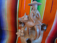Mexican vintage folk art, and Mexican vintage pottery and ceramics, a candlelabra in the form of a lovely woman riding atop her steer, attributed to the great Heron Matinez during his burnished natural period, Acatlan, Puebla, c. 1950's. A side view of the piece.