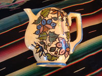 Mexican vintage pottery and ceramics, a beautiful coffee pot with a cream-colored background glaze and exquisite floral decorations, Tlaquepaque, Jalisco, c. 1940's. View of the side of the pot, lying down on one side.