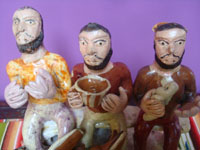 Mexican vintage folk art, a pottery sculpture of three men with a playful devil in front (possibly representing the Trinity of Father, Son, and Holy Spirit), Ocumicho, Michoacan, c. 1950's. Closeup photo of the three men's faces.