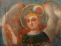Mexican vintage devotional art, and Mexican vintage tinwork- art, a beautiful retablo depicting the Archangel Rafael, in a stunning tinwork-art frame with reverse painting on the glass border, c. 1880-1900.  A closeup photo showing the face of the angel.