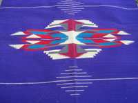 Vintage New Mexican textiles, a lovely woolen textile from the weaving center of Chimayo, New Mexico, c. 1930's. The weaving has a beautiful and very rare purple background, with colorful Chimayo-style design elements in various wonderful colors. Closeup photo of the central medallion.