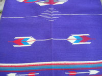 Vintage New Mexican textiles, a lovely woolen textile from the weaving center of Chimayo, New Mexico, c. 1930's. The weaving has a beautiful and very rare purple background, with colorful Chimayo-style design elements in various wonderful colors. Closeup photo of one of the design elemts, resembling an arrow.