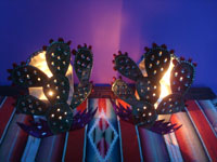 Mexican tinwork art, tin Oaxacan candle holders, Oaxaca, c. 1990. Photo of the candlholders lit by a candle.