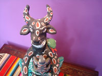 Mexican vintage folk art, a wonderful pottery sculpture from Ocumicho, Michoacan, depicting a playful devil with a snake wrapped around his head, a reptile crawling up his stomach, and a pesky rodent holding on to his knees, Ocumicho, Michoacan, c. 1970. Closeup photo of the devil's face.