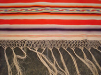 Mexican vintage textiles, and Mexican vintage Saltillo serapes (sarapes), a stunning Saltillo serape with color-hues of soft-red, lilac, purple, green, and soft-yellow, c. 1910-20.  Closeup view of one end of the serape, showing the beautiful fringe.