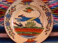 Mexican vintage pottery and ceramics, a very fine pottery plate featuring a leaping wolf, a blue bunny, butterflies and lovely foliage, with a starry-night background, from Tlaquepaque, Jalisco, c. 1920's. Closeup photo of the front of the plate.
