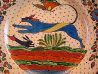 Mexican vintage pottery and ceramics, a very fine pottery plate featuring a leaping wolf, a blue bunny, butterflies and lovely foliage, with a starry-night background, from Tlaquepaque, Jalisco, c. 1920's. Another closeup photo.