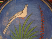 Mexican vintage pottery and ceramics, a lovely burnished plate with a beautiful blue background and wonderful artwork, Tonala or Tlaquepaque, Jalisco, c. 1930's. The artwork features a graceful bird and flowers.  Closeup photo of the lovely bird amidst foliage.