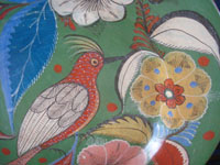 Mexican vintage pottery and ceramics, a beautiful burnished charger with an avocado-green background and phenomenal artwork featuring wonderful floral decorations with a tropical bird in the center, Tonala or San Pedro Tlaquepaque, c. 1930's. Closeup photo of the tropical bird at the center of the charger.