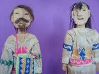 Mexican vintage folk art, a pair of carved wooden figures in traditional Huichol costumes, Nayarit, c. 1950's. Closeup photo of the faces of the figures.