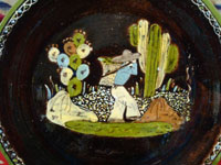 Mexican vintage pottery and ceramics, a blackware plate with wonderful artwork from Tlaquepaque, Jalisco, c. 1930-40's. The plate has a beautiful border and a scene of a campesino carrying his heavy load amidst plants and cacti.  Closeup of central scene.