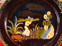 Mexican vintage pottery and ceramics, a blackware plate with wonderful artwork from Tlaquepaque, Jalisco, c. 1930-40's. The plate has a beautiful border and a scene of a campesino carrying his load of wood amidst plants and cacti. This is the second of three plates, probably all by the same great artist. Closeup photo of the central scene.