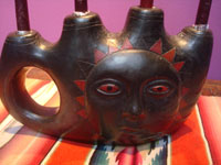 Mexican vintage folk art, a lovely blackware pottery candlelabra with a wonderful image of the sun on the front, Oacaca, c. 1950's. Closeup photo of the base showing the face of the sun.