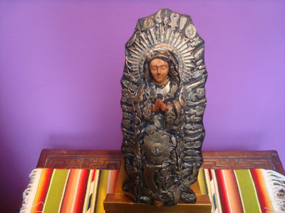 Mexican vintage devotional art, a beautiful woodcarving of Our Lady of Guadalupe decorated with hundreds of milagros, Mexico, c. 1950.